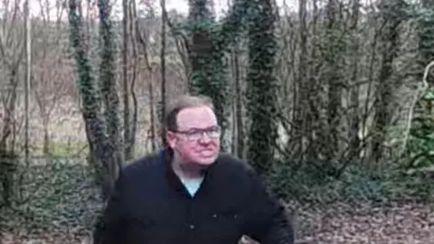 RSPCA CCTV footage of a white man wearing a wearing glasses, a dark jacket and light blue t-shirt