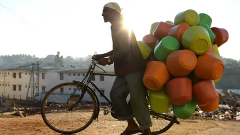 Getty Images This photo taken in March 2015 shows a vendor carrying colourful plastic water pots on his bicycle to sell to households in Bangalore.