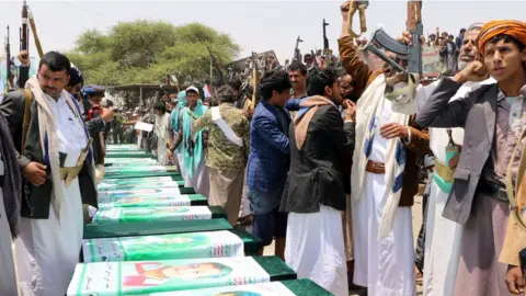 AFP Men raise their rifles next to coffins in the northern Yemeni city of Saada on 13 August 2018