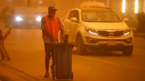 Getty Images An Iraqi cleaner works to clean the street during a severe dust storm in the Iraqi capital Baghdad