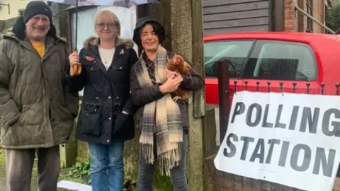 Woman holds chicken at polling station