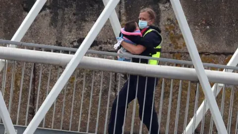 PA Media A child being carried ashore