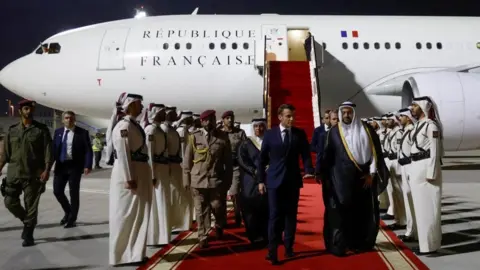 Reuters French President Emmanuel Macron is welcomed by officials of the Ministry of Foreign Affairs upon his arrival at Doha's airport, for a one-day visit to discuss with the Emir of Qatar
