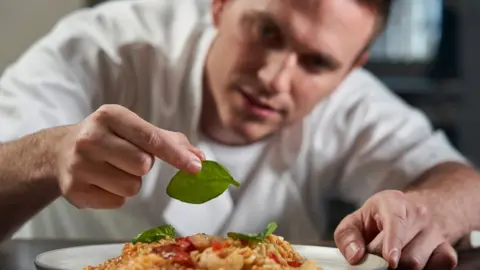 Getty Images Chef places leaf on cooked dish