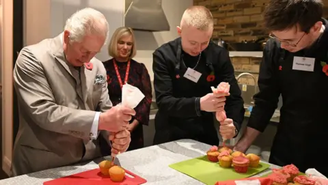 PA Media Prince Charles ices cupcakes made by young people on one of the courses.