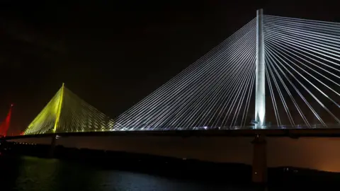Reuters The new bridge was illuminated on Monday to mark the ceremonial handover to the Scottish government