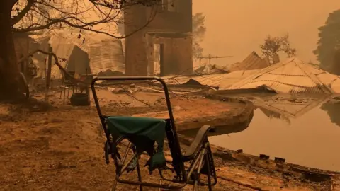 RAPHAEL KORMAN Burnt out chair in a front of a destroyed property in Mallacoota