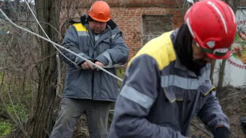 Getty Images Workers repair broken power lines in Tatianovka village near Svyatohirs'k in Donetsk region on November 25,