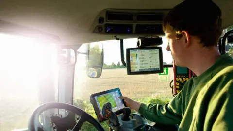 Getty Images Farmer uses GPS in tractor