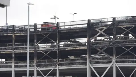 PA Media A view showing the top level of the car park and some levels below. Burned out cars and collapse of floors can be seen.