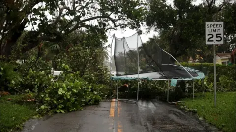 Getty Images Trees and a trampoline are pictured blown into a road