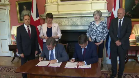 The DUP's Sir Jeffrey Donaldson and Gavin Williamson of the Conservative Party sign a deal in Downing Street