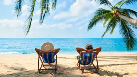 Getty Images Two people on deck chairs on the beach