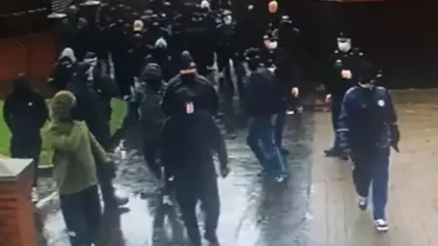 BBC Police could be seen monitoring the scene as the masked men walked in the area