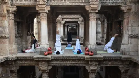 Getty Images Indian yoga practitioners take part in a yoga session on International Yoga Day at the 15th century Adalaj Stepwell in Adalaj, some 40km from Ahmedabad in western Gujarat state, on June 21, 2019.