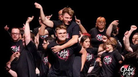 The Cube Disability Young people in black "Cube Love" T-shirts on stage