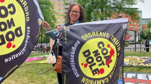 Phil Bodmer/BBC Woman holding flags for The Orgreave Truth and Justice Campaign