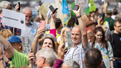 PA Media Protesters set off their mobile phone alarms at the same time to highlight the issue