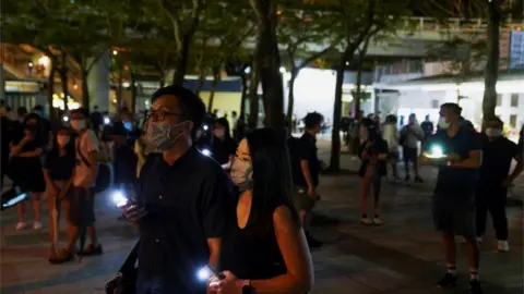 Reuters People gather with their phone lights on near Victoria Park, June 2021