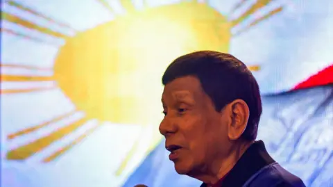 Getty Images Former president of the Philippines Rodrigo Duterte delivers a speech with a Philippine flag in the background