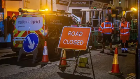 A picture of the scene where a road was closed. A National grid van and workers can be seen.