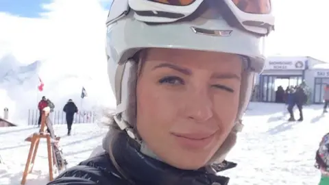 NCA Ekaterina Zhdanova on the ski slopes, winking at the camera.