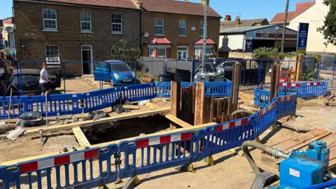 Blue roadworks fencing surrounding a large pile in the middle of a residential street.