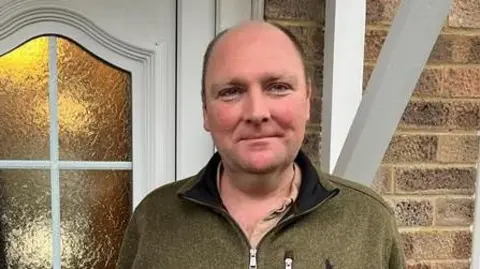 Philip Oostenbrink stands outside his front door on Woods Ley in Ash