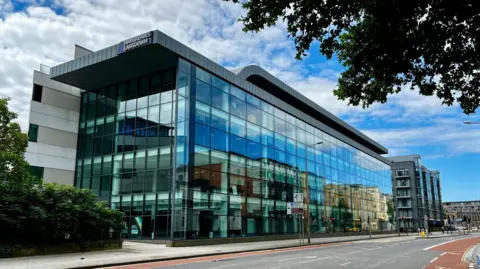 Hargreaves Lansdown Bristol HQ - a mainly glass building - with a road in front of it