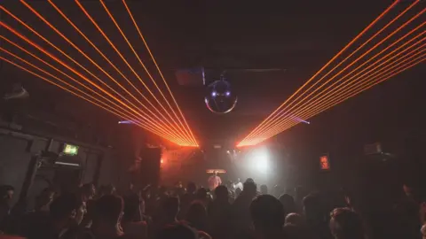 The Hare and Hounds Red lasers appear over a crowd of people dancing in a dark room with a disco ball on the ceiling.