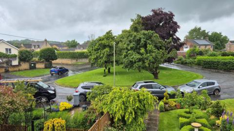 SATURDAY - Rain falling in Long Hanborough looking out of a window at cars in a residential street