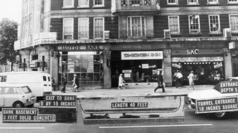 Getty Images Black and white archive image, showing a row of shops in 1971. Lloyds Bank is on the corner, then a chicken restaurant and then SAC, a leather goods retailer. The image has been notated to show the location of the tunnel beneath the road.