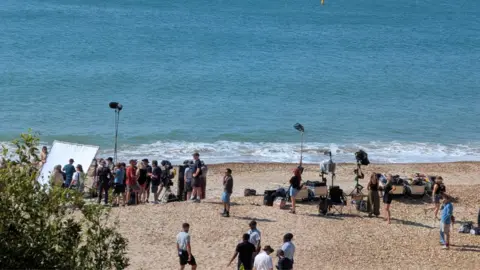 Film crews on a beach in Dorset on a sunny day