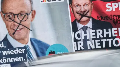 EPA-EFE Two posters on a street in Berlin show the conservative Friedrich Merz (L) and rival Social Democrat Olaf Scholz - both have been defaced with black X marks on their faces