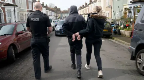 Police escort one of the teenagers from the car away from the scene