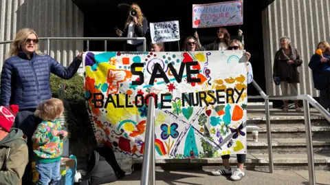 Protestors hold a sign saying save Ballogie nursery, as they protest a possible closure at Aberdeenshire Council