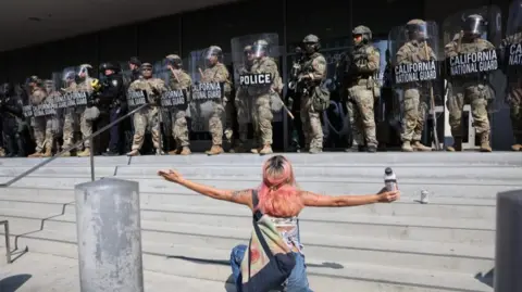 Woman kneels before guardsmen