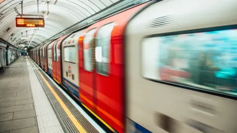 Stock photo of a Tube train in motion passing by an underground platform. 