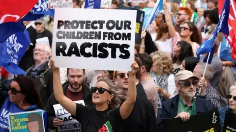 Reuters Protesters hold placards including one reading 'Protect our children from racists' during the Belfast Welcomes Diversity anti-racism protest in Belfast 