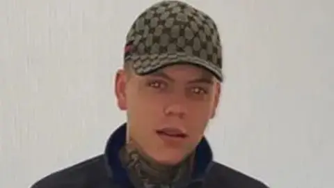 Family handout Shane Finn looks at the camera. He is clean shaven and wearing a green checked baseball cap