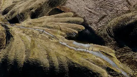 Jon Pountney drone shot of a former spoil heap now covered with grass, forming a pattern like fingers in the landscape