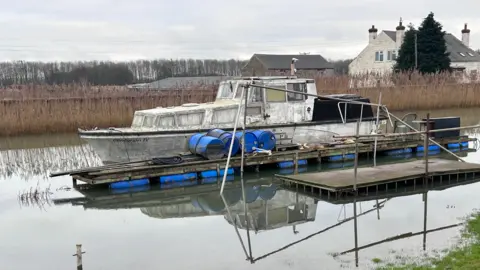 A boat that has been abandoned which looks like it is going to sink.