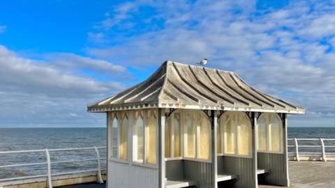 Partly cloudy sky on a beach hut on a pier next to the sea