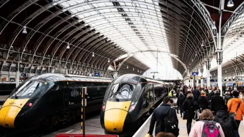 Two GWR trains are parked in a station. There are a lot of people on the platform.