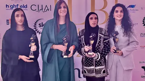 A group of woman stand holding their awards.