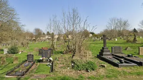 A large area of with grass with several headstones indicating burial plots.