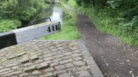 A muddy path alongside a canal lock