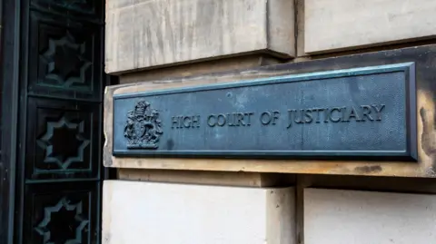 Getty Images A grey metal sign on an exterior wall of the High Court in Edinburgh. The sign reads: High Court of Justiciary.