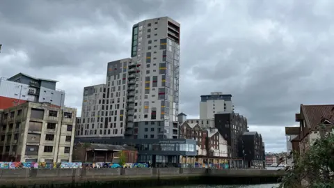 Shaun Whitmore/BBC Ipswich waterfront image showing the Mill, a tall white building with a lot of windows along the Waterfront. Other smaller buildings site either side