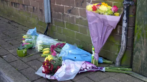 PA Media Floral tributes near the scene in Paradise Road.